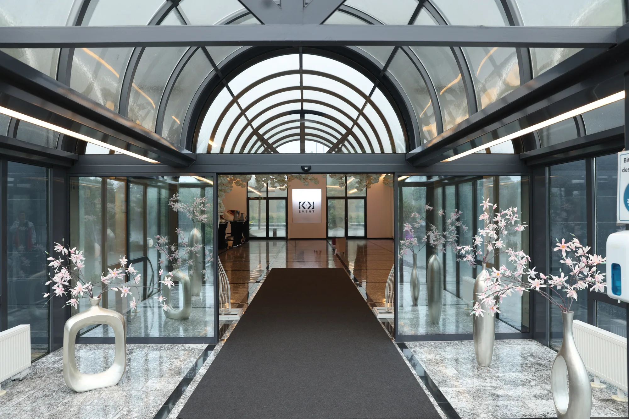 Eleganter Eingang zum Foyer mit Glasarkade und Blumendekoration
